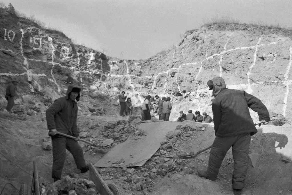 Black and white photo of two men digging at the Zhoukoudian archaeological site