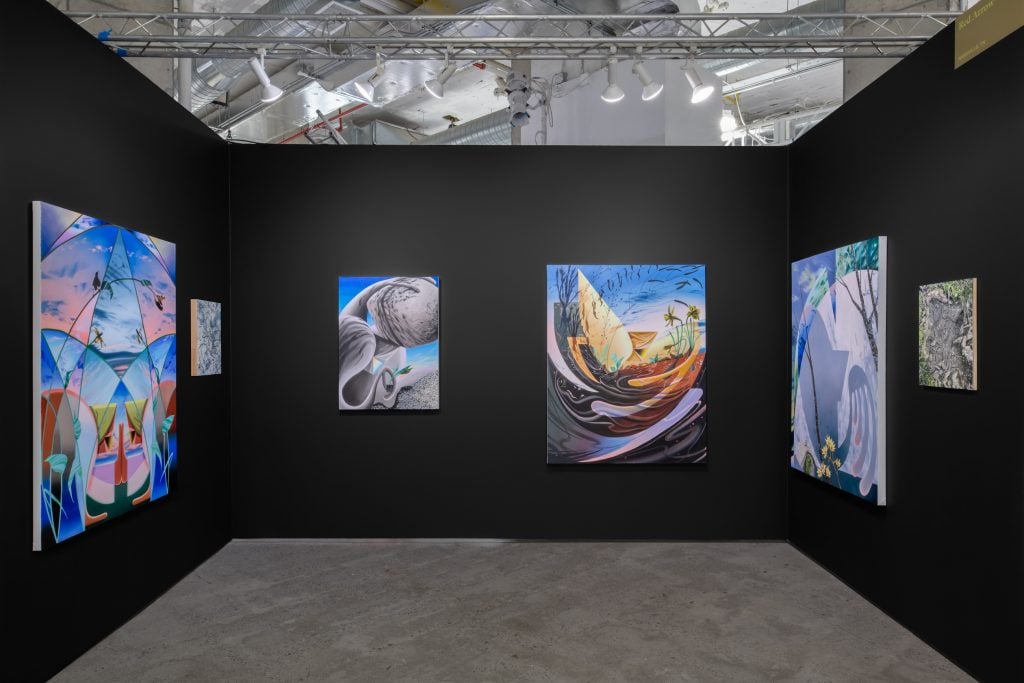 An art fair booth with several paintings on darkened walls