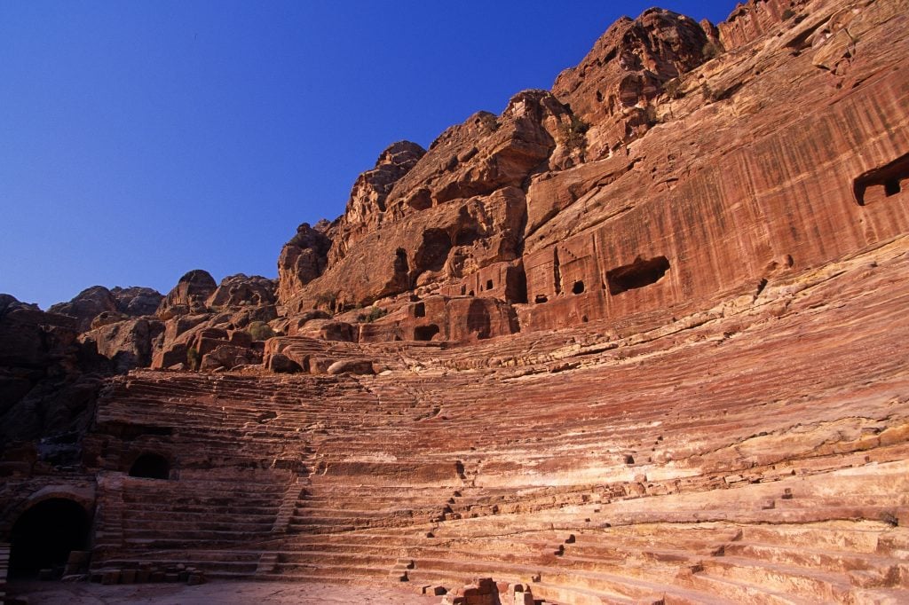 An amphitheater cut out of red rock against a blue sky