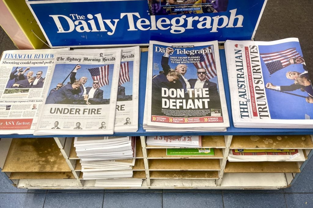 A newstand full of newspapers with images of a man raising his fist