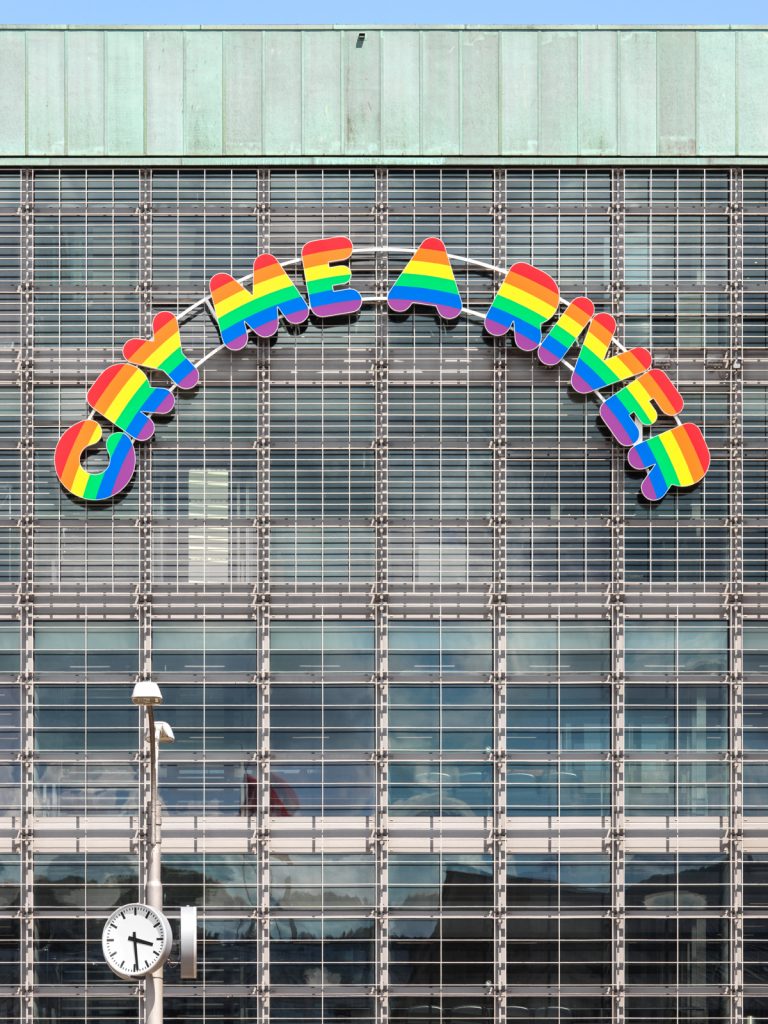 Artwork by Swiss artist Ugo Rondinone installed on the front of the museum, oversized rainbow-striped letters in an arch like a rainbow reading: cry me a river.