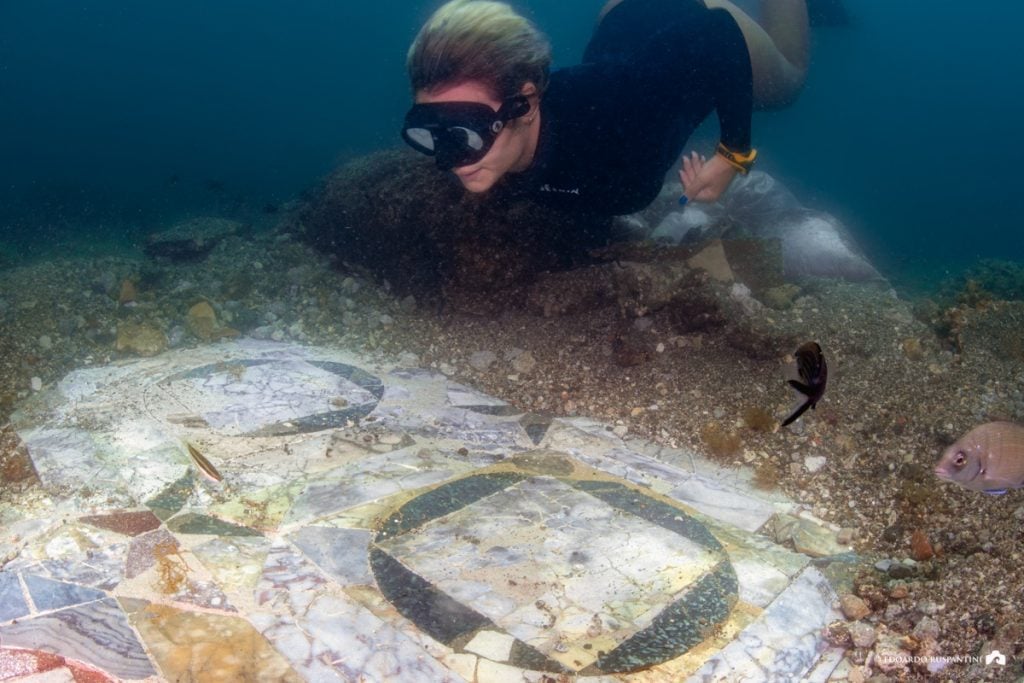 A diver swimming above a Roman mosaic floor underwater