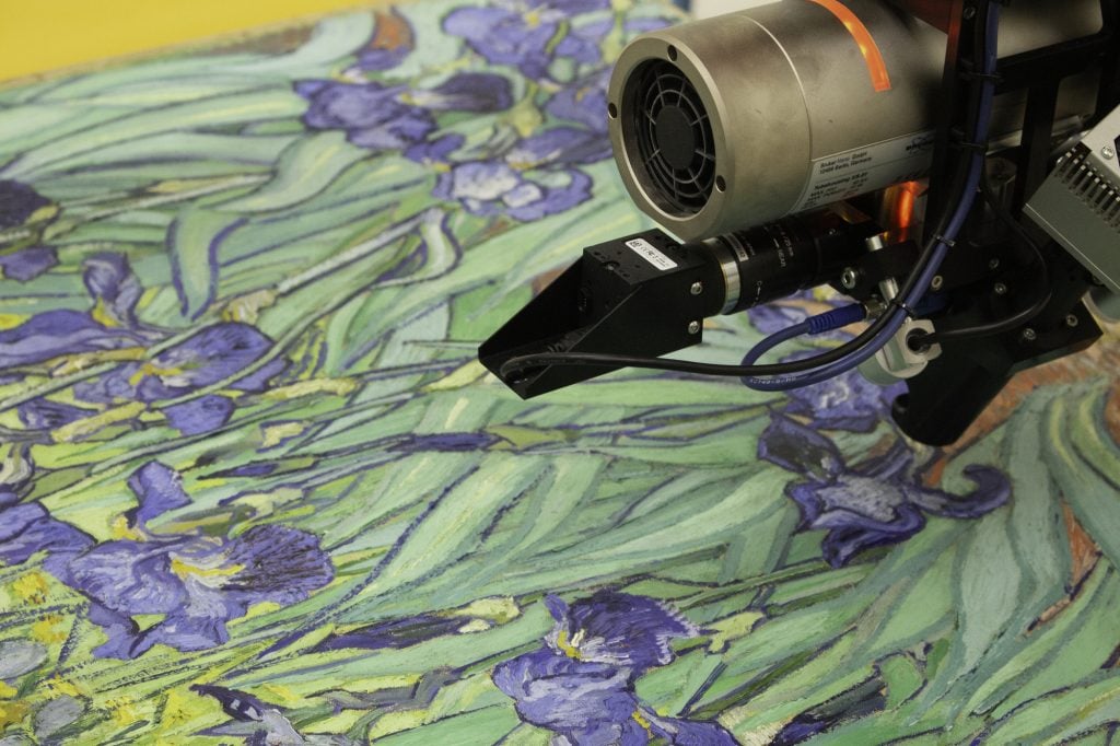 A microscopic tool positioned over Van Gogh's painting, Irises.