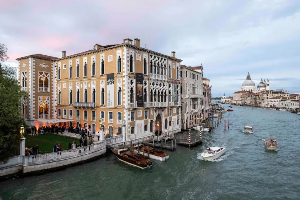 The ACP Palazzo Cavalli-Franchetti in Venice, an ornate mansion sitting on a canal with boats going by. 
