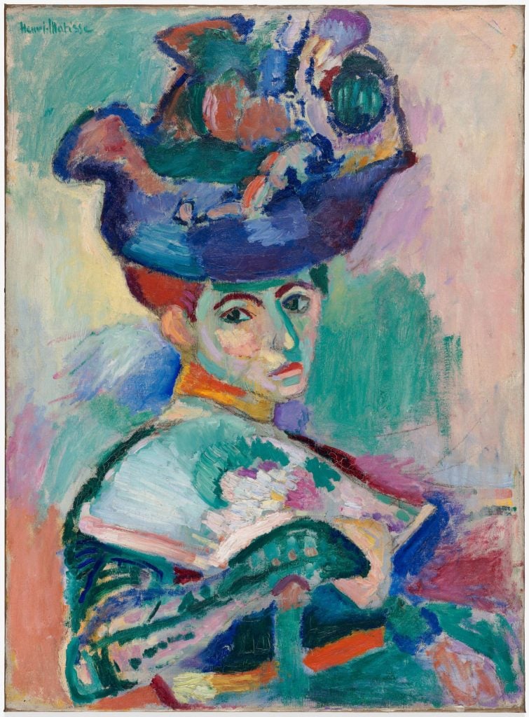 A key Fauvism portrait by Henri Matisse showing a woman in a hat, painted in unnatural colors