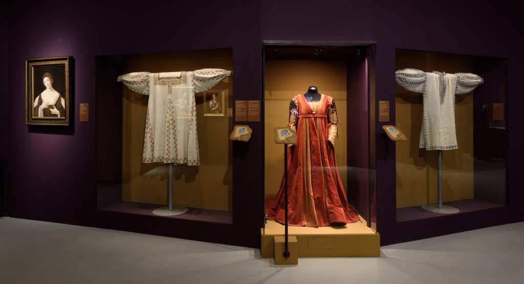 a large red dress in a glass case in a museum