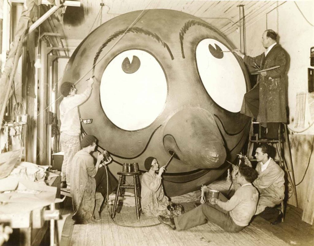 Tony Sarg and his assisstants stand in front of a balloon painting it