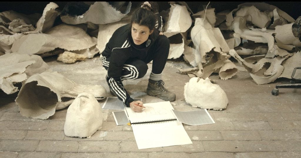 the artist Giulia Cenci squats and draws in front of discards of her work