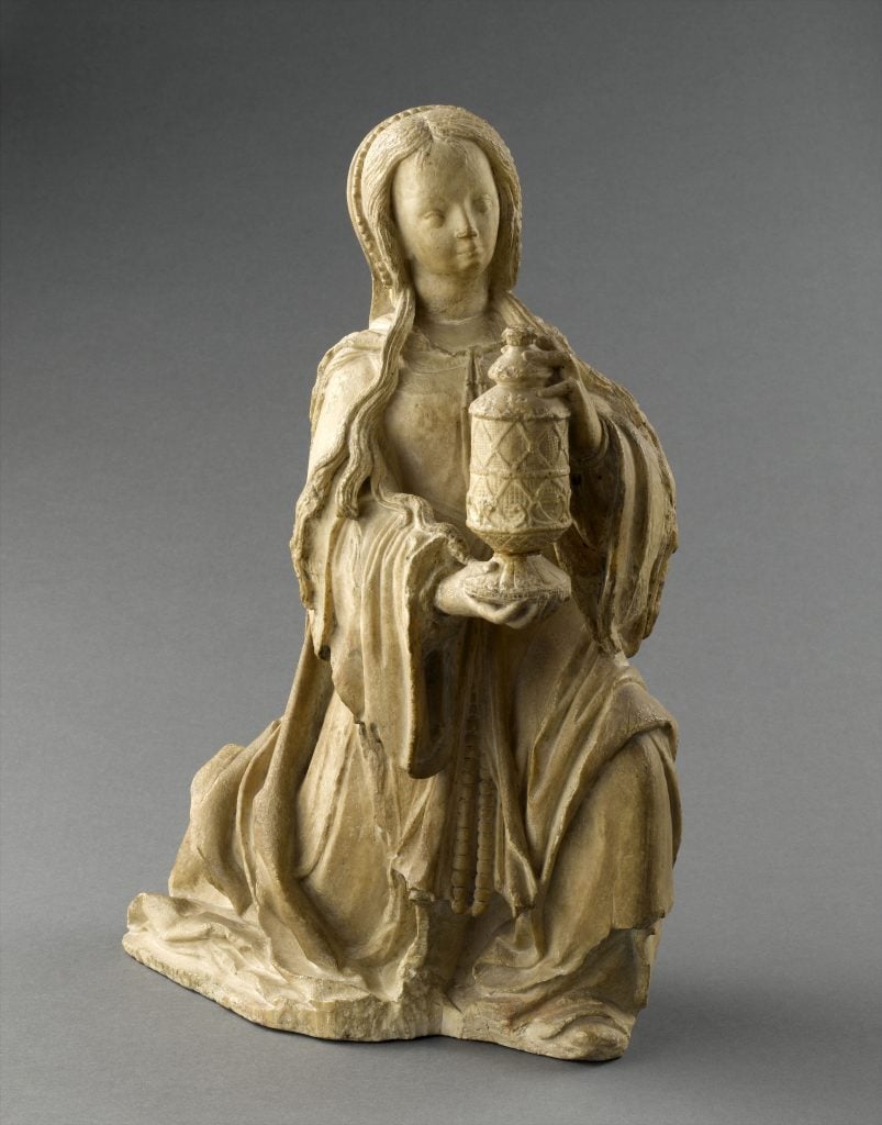 A small statue of Saint Mary kneeling and holding an incense burner