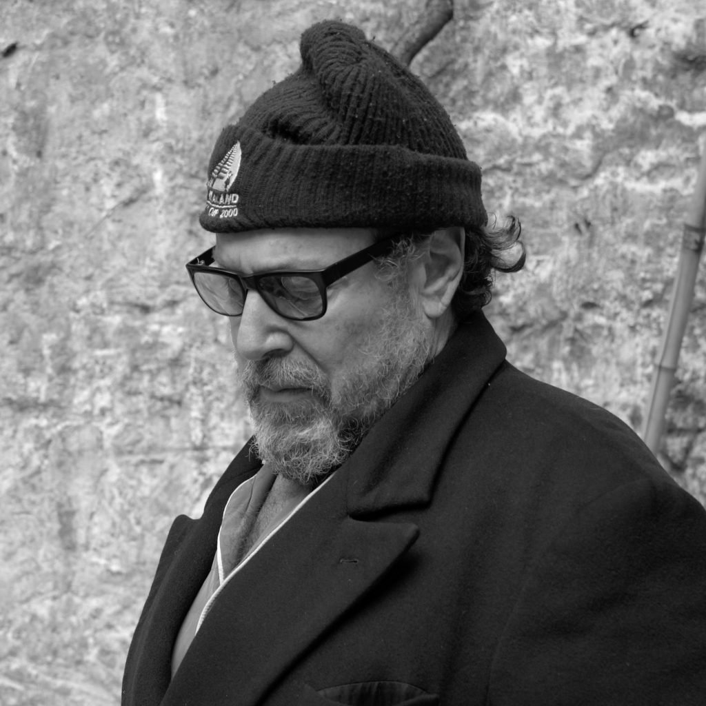 Black and white photograph of artist Julian Schnabel, a man with a greying beard in a beanie