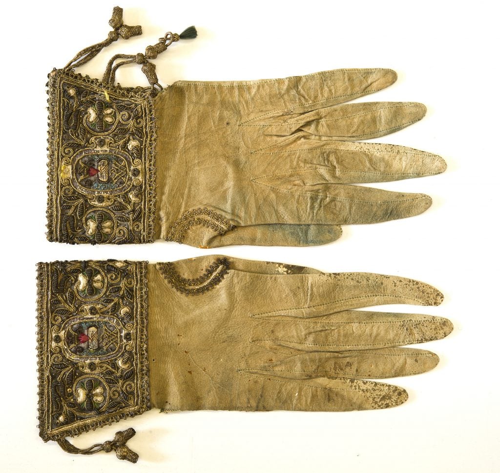 A pair of 17th century ladies' gloves made of gold-coloured silk, with elaborate embroidery on the wrists