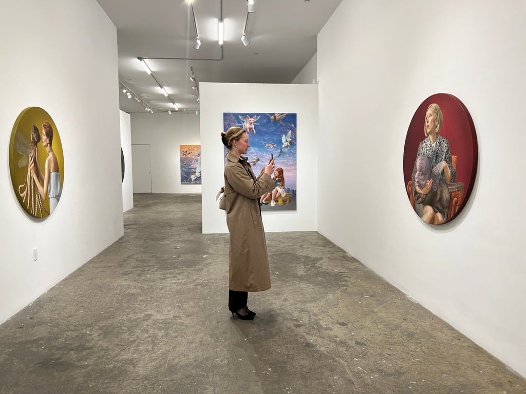 a woman taking a photo of paintings depicting women holding chimera pets