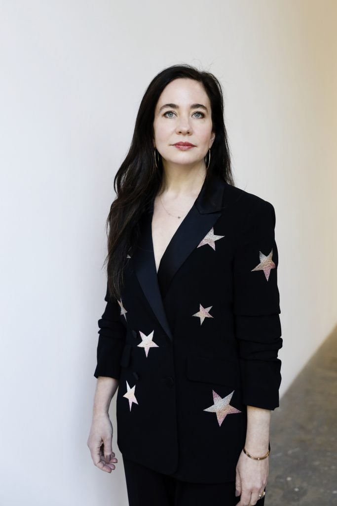 A woman in black blazer with silver stars and long black hair