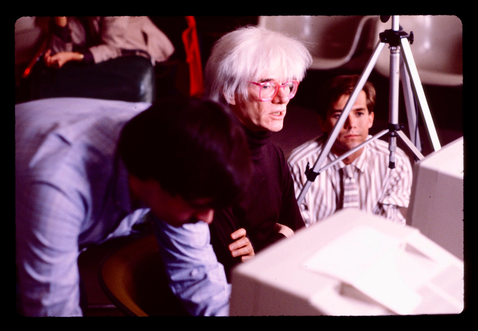 an image of Warhol sitting in front of a computer