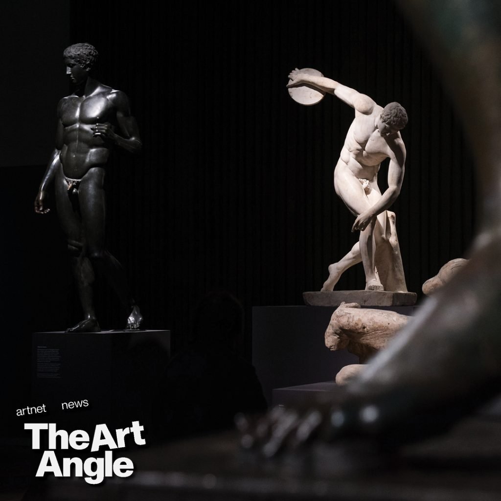 a white marble copy of a man throwing a discus is seen in dramatic lighting