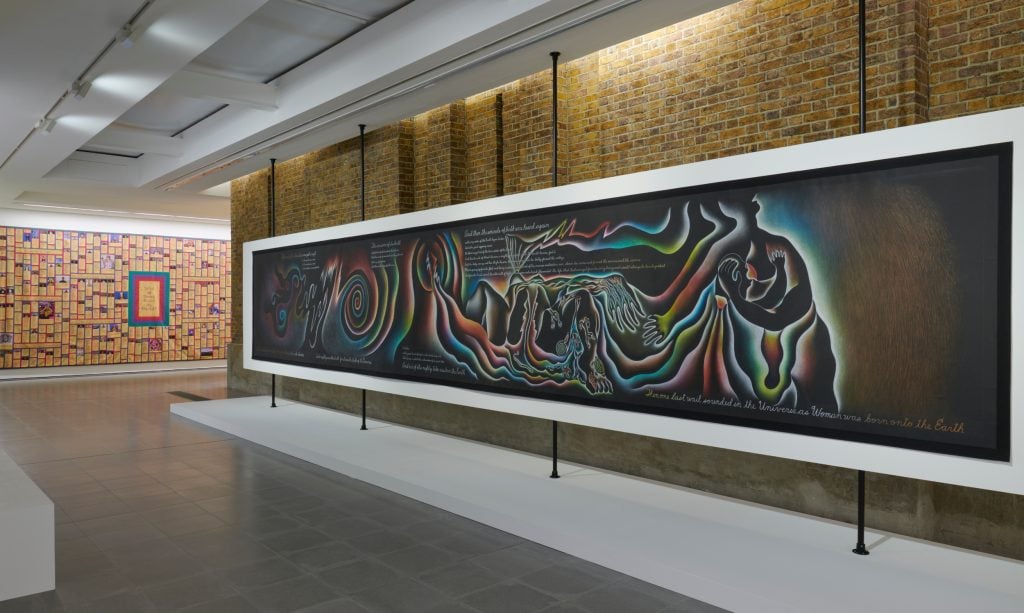 a gallery space with bare brick and then a long painting running along the wall