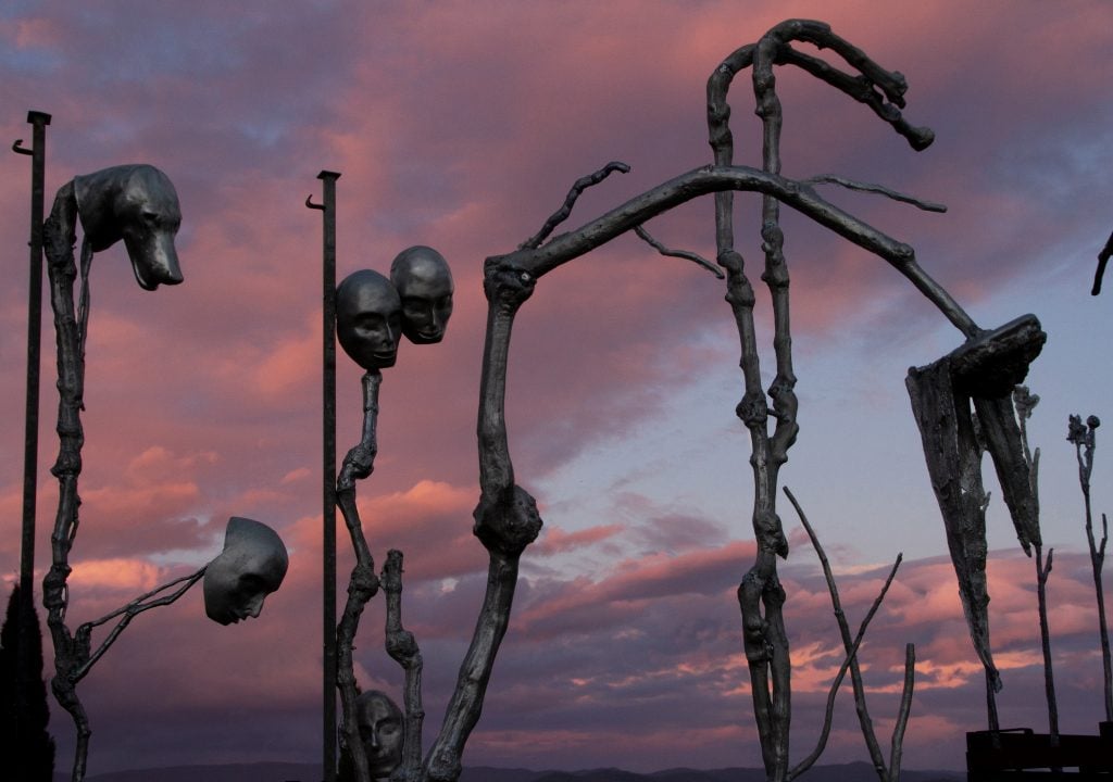 a skeletal sculpture is ominous set against the maroon night sky