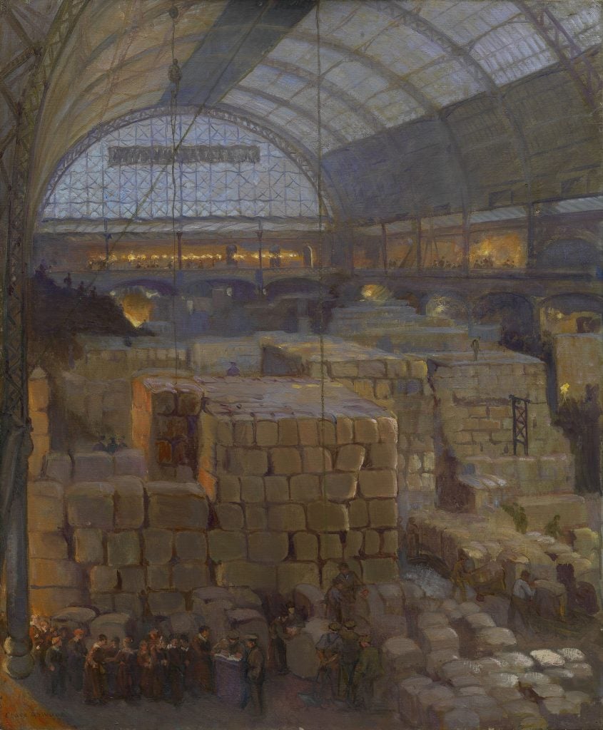 the inside of an industrial depot piled high with parcels, the large interior space is clearly the arched, glass interior of a train station