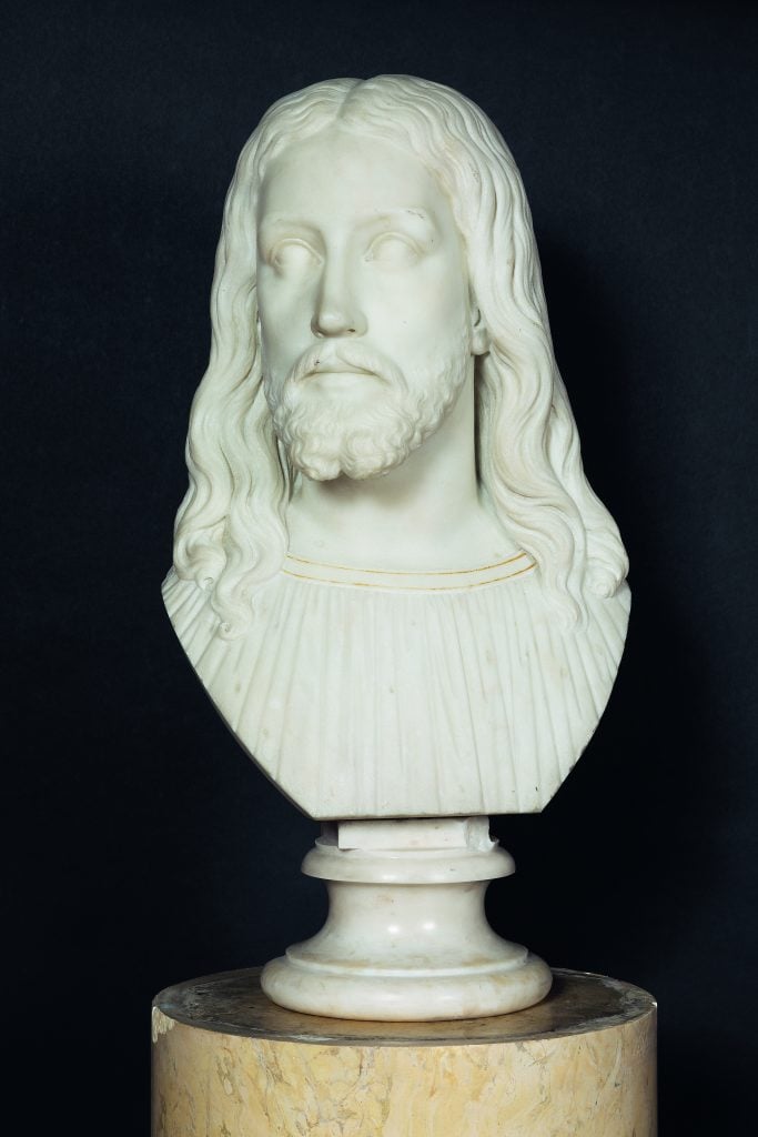 a marble bust of a man with long hair against a black background