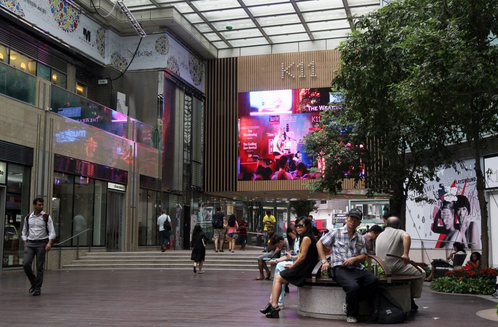 people sit on benches and walk through a large shopping mall