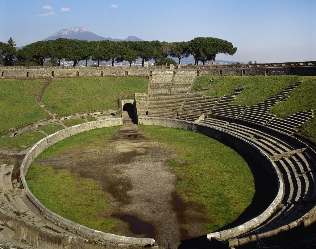 images of Amphitheatre inside pompeii it is in good conition with grass growing in central area and umbrella pines visible in the background