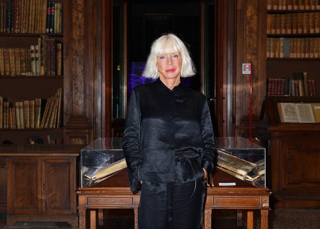 a blonde woman stands in a library