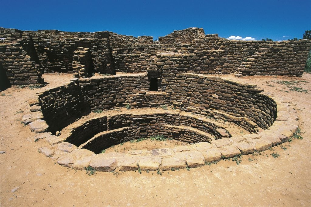 a kiva, round space dug in ground, in the context of a village of stone that was abandoned