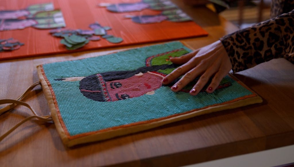 a woman artist's hand rest on artworks with Native American imagery.