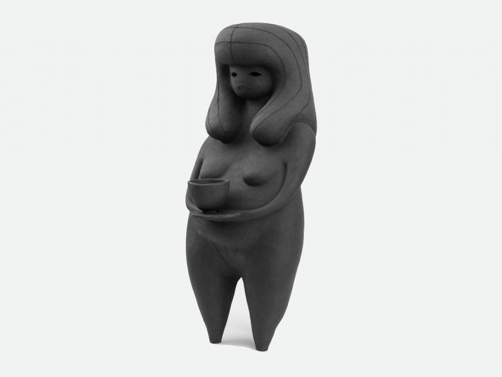 This image depicts a sculpture in the shape of a woman in long hair, dark colour