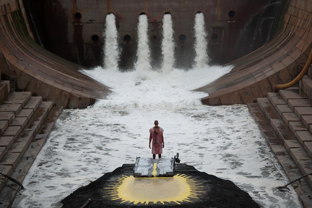 a man stands at an altar in a cavernous room of pulsing water