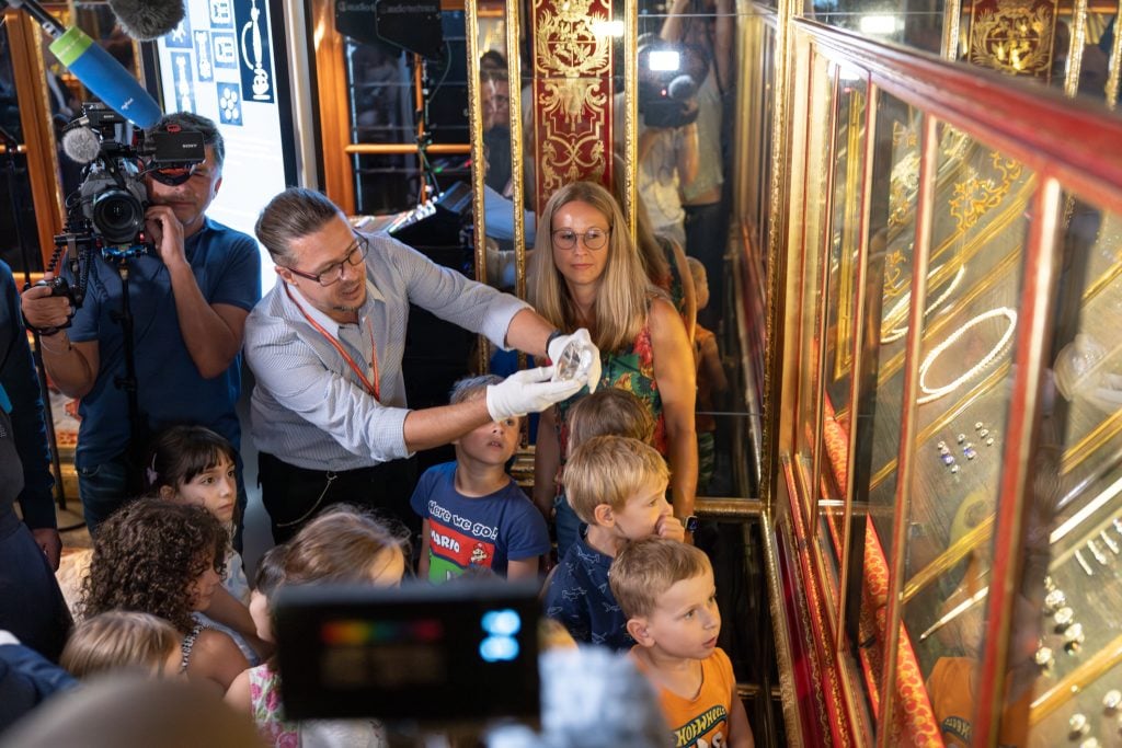 man showing jewels to children at a museum