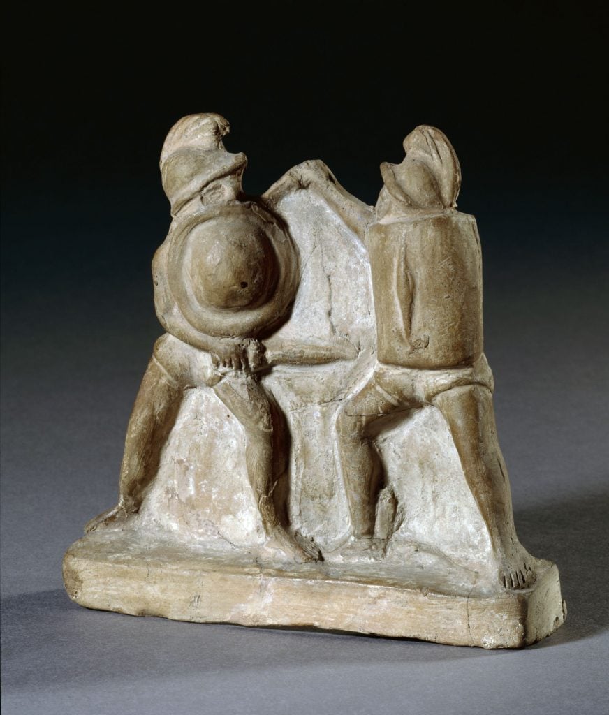 a sculpture of two little figurines dressed as gladiators fighting