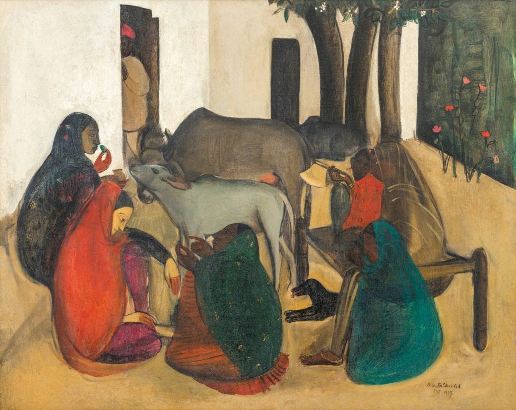 an image of women sitting on the ground and talking as goats linger nearby