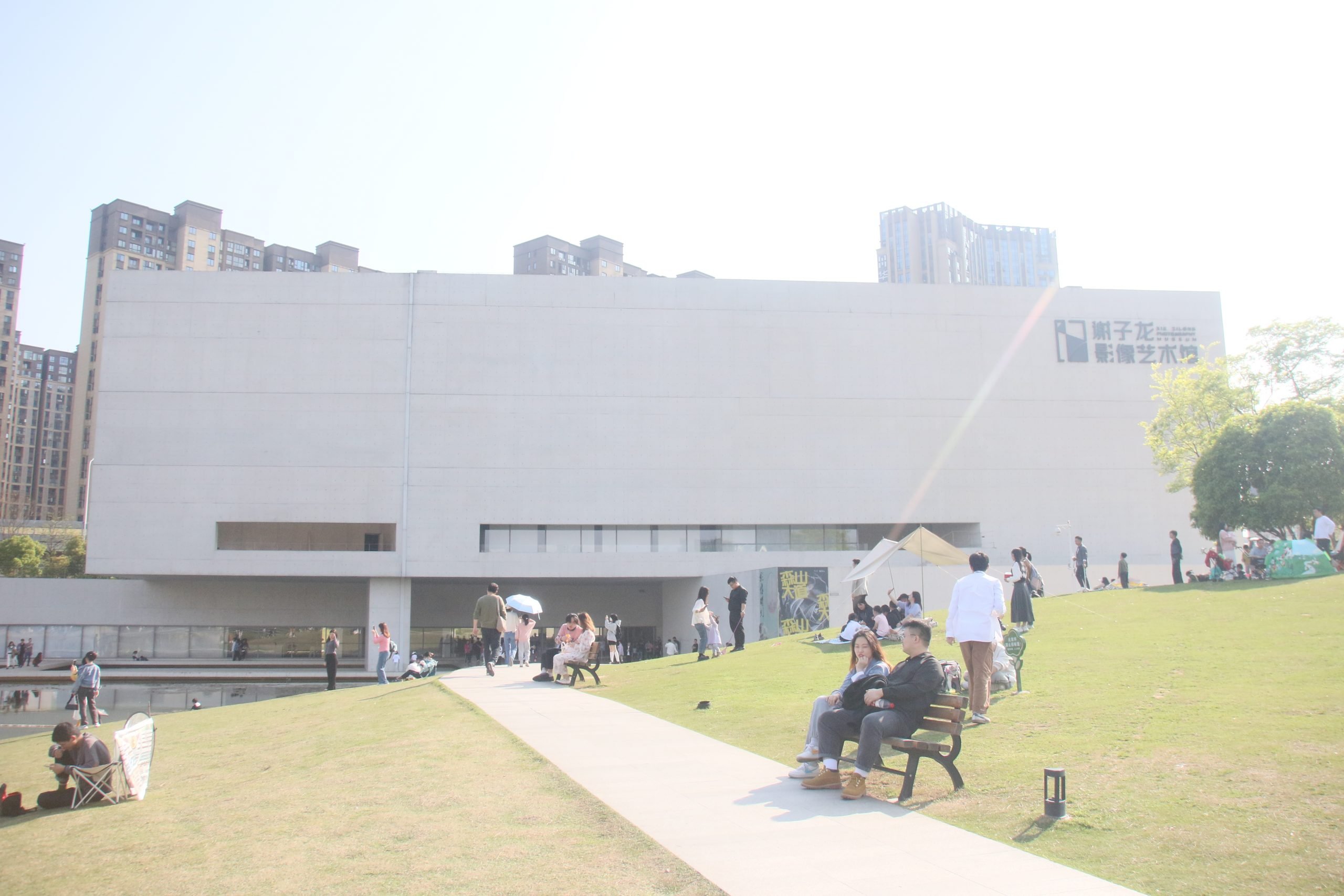 This photo depicts a white building and the green grass land in front of the building.