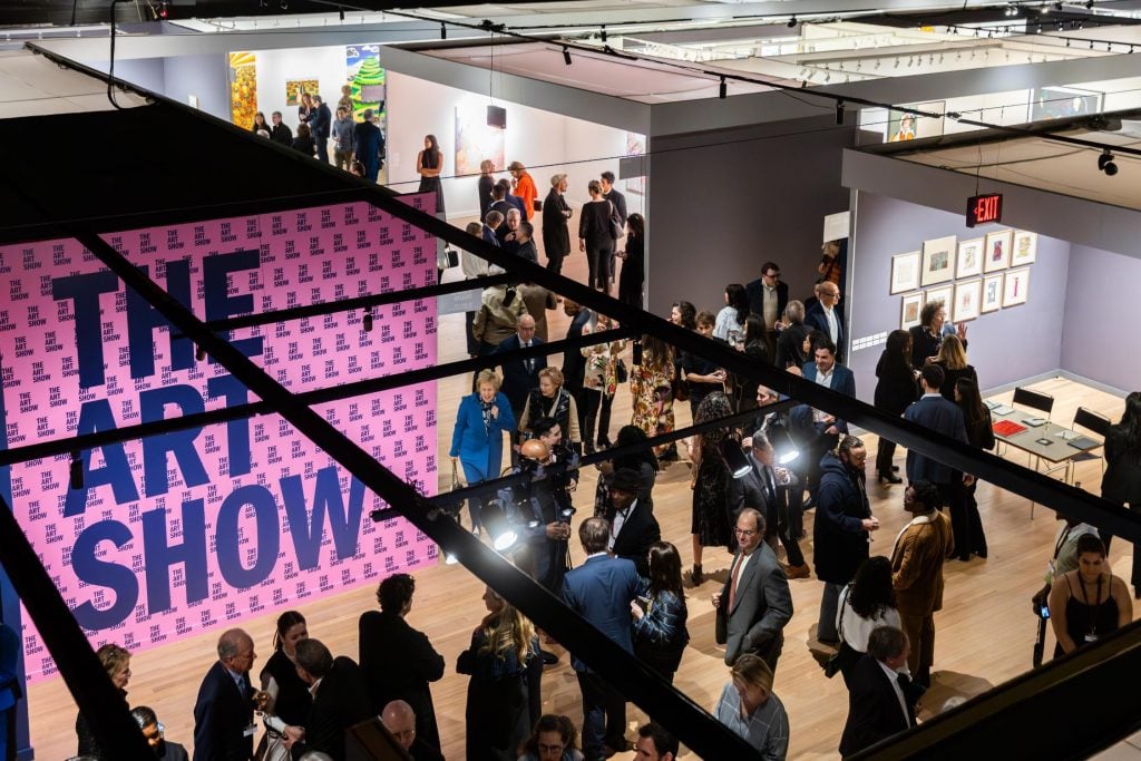 A crowd of people in the aisles and booths at an art fair