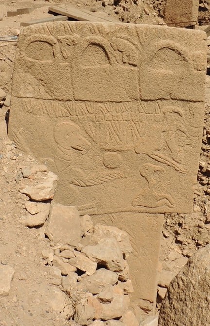 A close up photograph of pillar 43 at Göbekli Tepe, with carvings including v shapes, boxs, and a bird