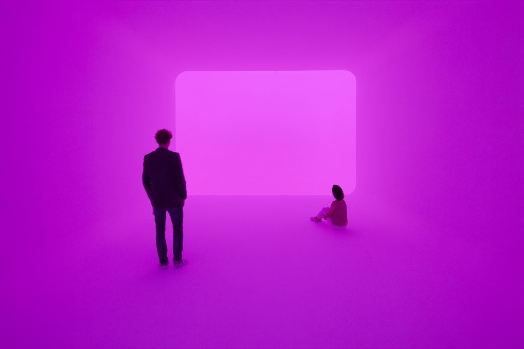 Two people standing in a room with colored light