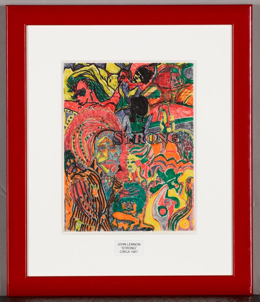 A photograph of a colorful framed drawing that John Lennon made with the label 1967 on the white paper inside its red matte