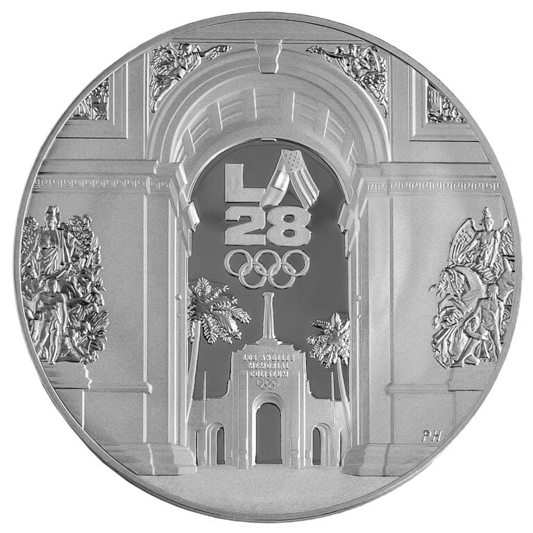 The reverse of the the official LA28 Handover Medallion, designed by mint medallic artist Phebe Hemphill. The coin shows the Arc de Triomphe in front of the Los Angeles Coliseum and palm trees, with the Olympic rings below the words "LA 28."