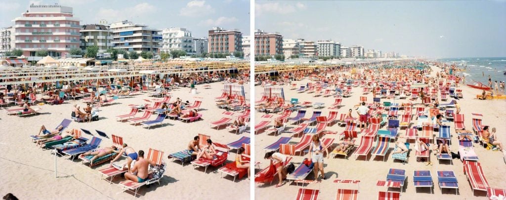 A two-part photograph by Massimo Vitali showing a beach scene with multicolor beach chairs and cabanas lined up on the beach, and on the horizon a row of buildings.