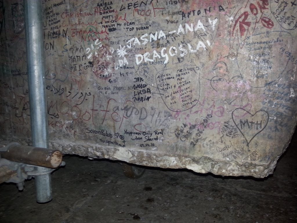 A large stone slab blanketed with various graffiti