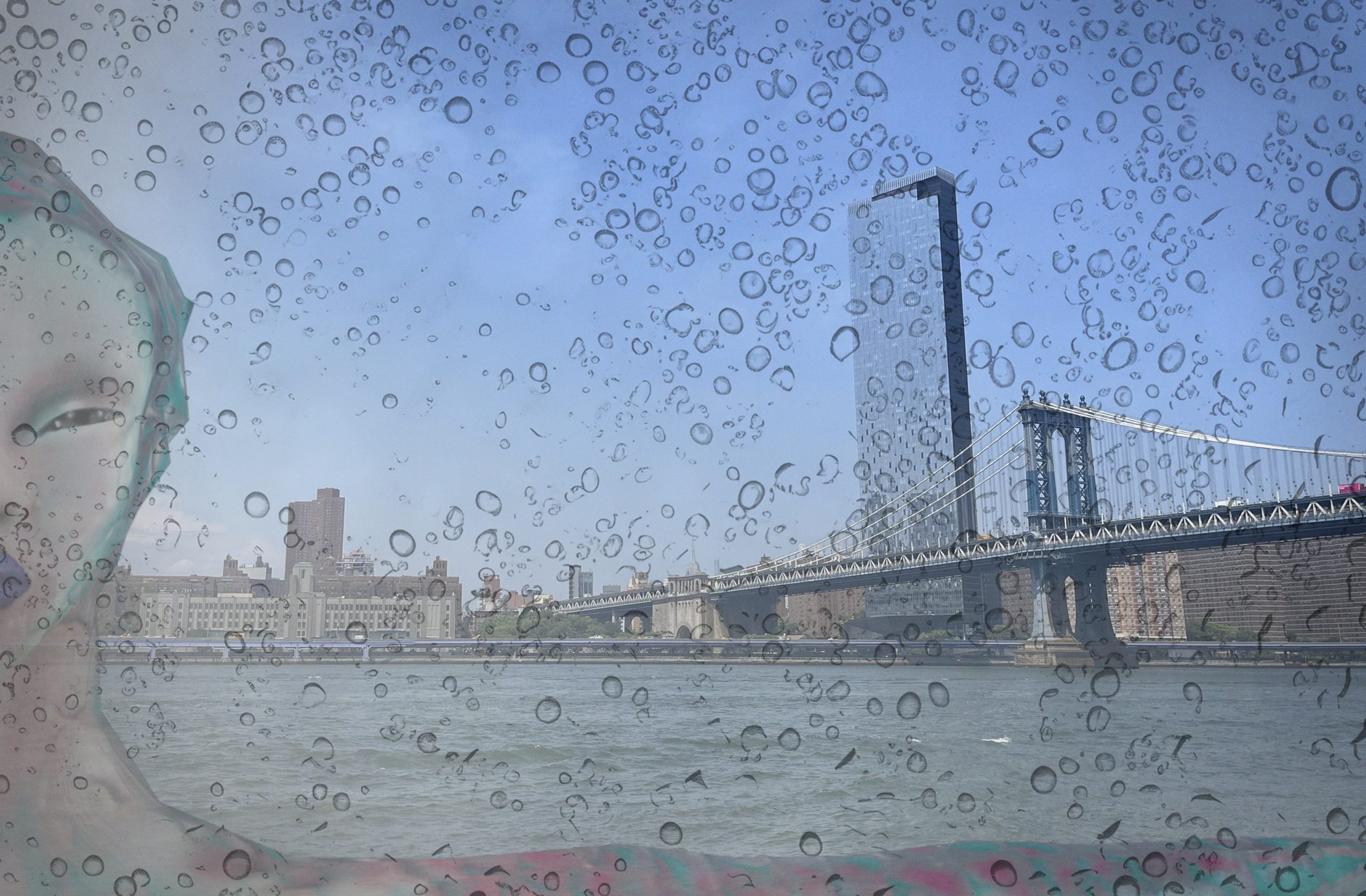 An AR image of a digital sea creature in close up before the East River and downtown Manhattan skyline, with water droplets covering the window through which the scene is viewed