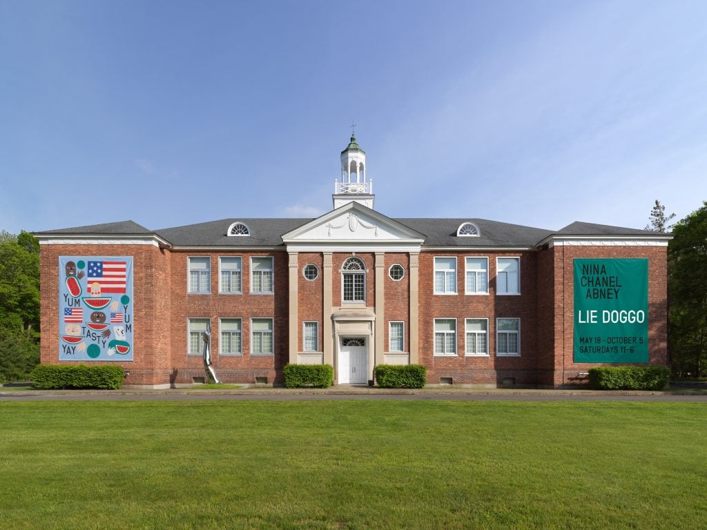 a large brick school house in a georgian style with a green lawn in front of it