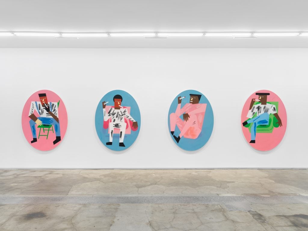 a series of tondo, circular artworks in hues of pinks and blues, installed on a gallery wall
