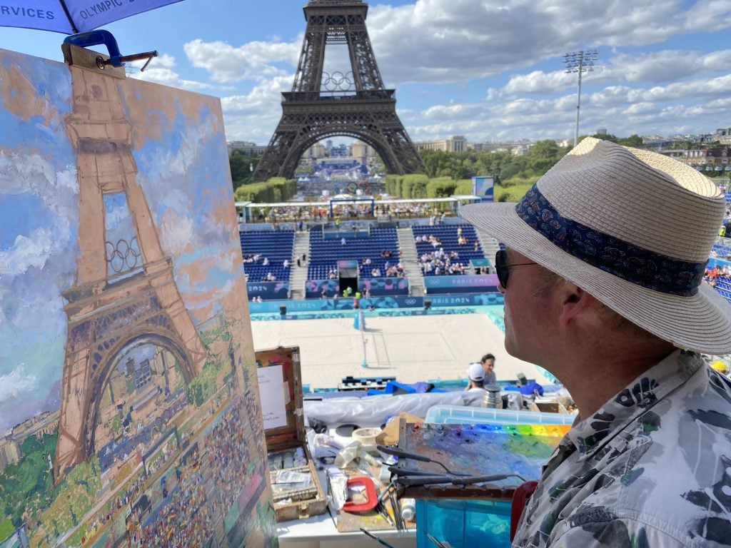 Peter Spens painting the Olympic beach volleyball tournament, with a view of the Eiffel Tower.