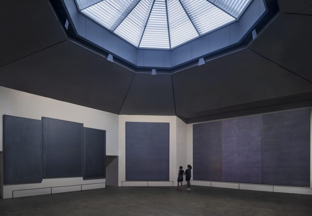 The interior of the Rothko Chapel, showing dark mural paintings and a skylight