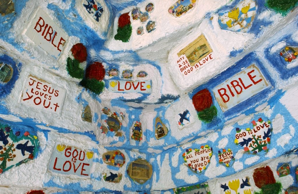 A wall decorated with painted flowers and phrases such as "Bible," "God Is Love," and "Love"