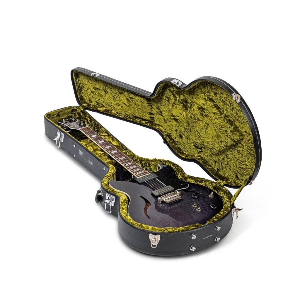 A photograph of a black guitar in a black case lined with crushed yellow velvet, on a white background