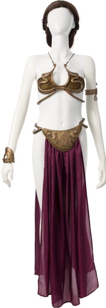 A gold bikini with silk front panel and bracelets displayed on a mannequin