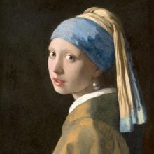 a painting of a woman in profile turning to look at us, she has her hair pulled back in a wrapped cloth that is blue and yellow and she is wearing a large pearl earring